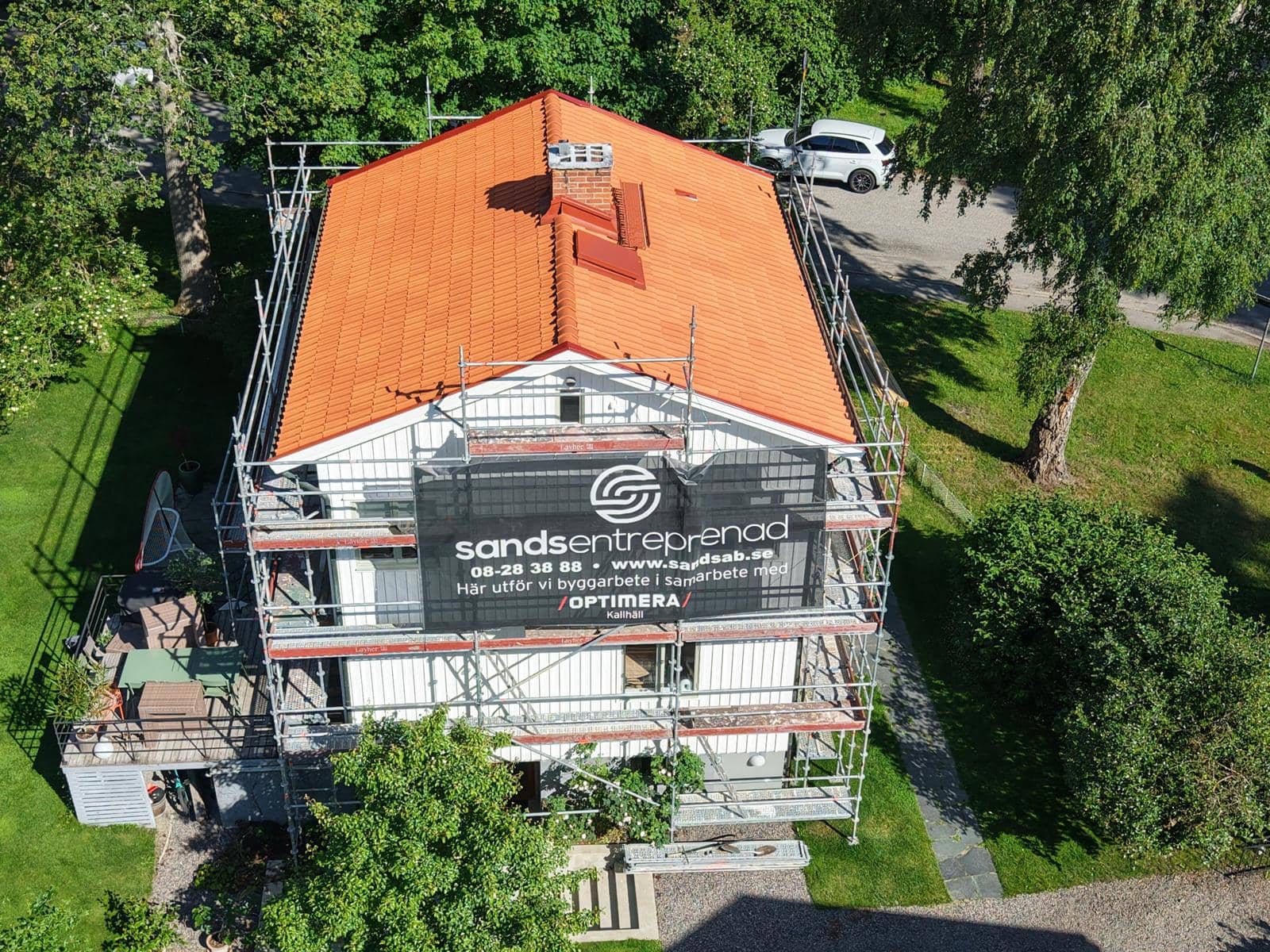 Nylagt tegeltak på villa i Bromma, sett från ovan med Sands Entreprenads ställningsbanderoll på fasaden